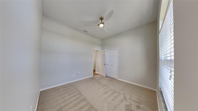 carpeted spare room with baseboards, visible vents, and ceiling fan