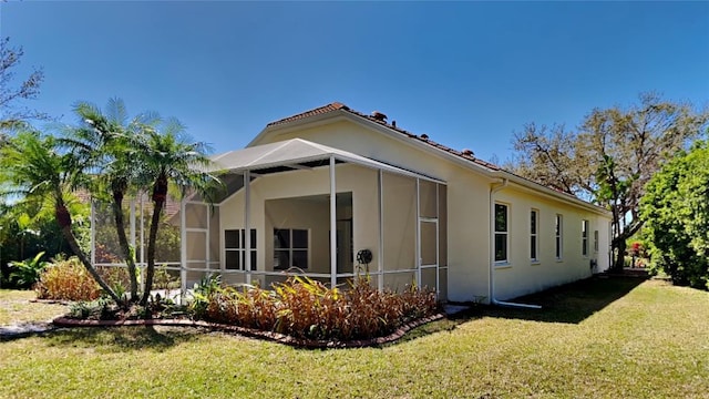 view of side of home featuring a lanai and a yard