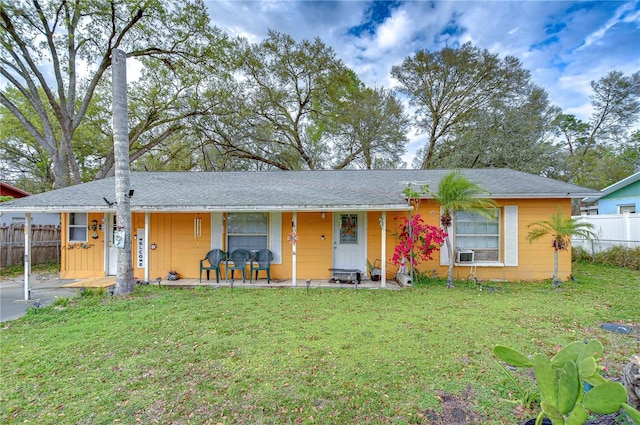 ranch-style house featuring a front lawn, cooling unit, and fence