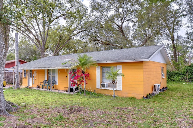 single story home with a front lawn, roof with shingles, and fence