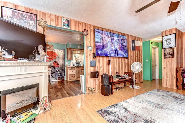 interior space with wooden walls, a fireplace, a textured ceiling, and wood finished floors