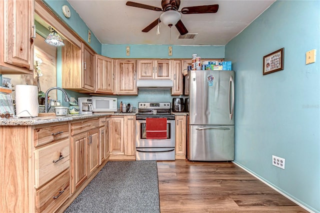 kitchen featuring stainless steel appliances, visible vents, light brown cabinetry, wood finished floors, and under cabinet range hood