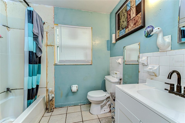 bathroom with shower / tub combo, toilet, tile patterned floors, vanity, and tile walls