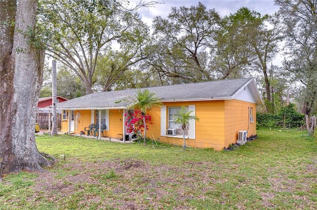 ranch-style home with a front yard, cooling unit, and fence