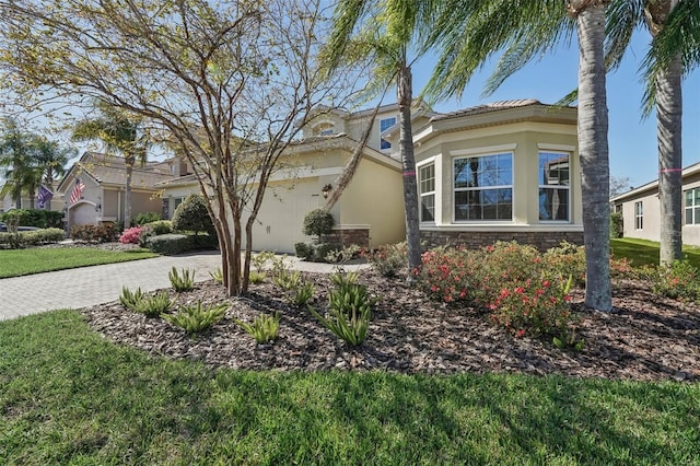 view of front of house with stone siding, a front lawn, decorative driveway, and stucco siding