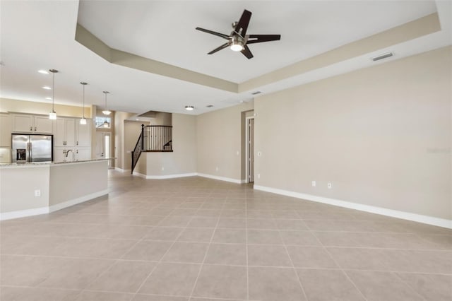 unfurnished living room with light tile patterned floors, baseboards, visible vents, ceiling fan, and stairs