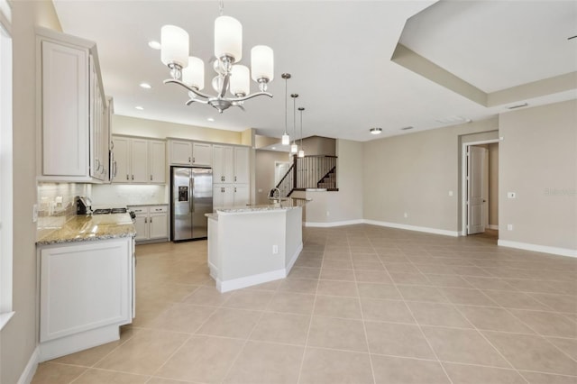 kitchen with light tile patterned floors, baseboards, open floor plan, stainless steel refrigerator with ice dispenser, and backsplash