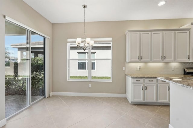 kitchen with light stone countertops, tasteful backsplash, baseboards, and decorative light fixtures