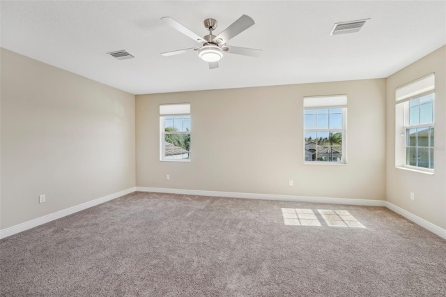 carpeted spare room featuring visible vents, ceiling fan, and baseboards