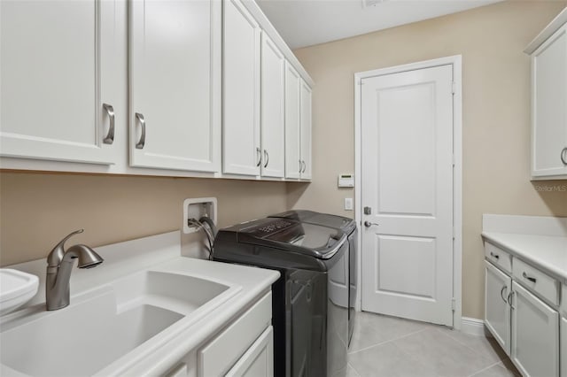 laundry room with washing machine and dryer, cabinet space, a sink, and light tile patterned floors