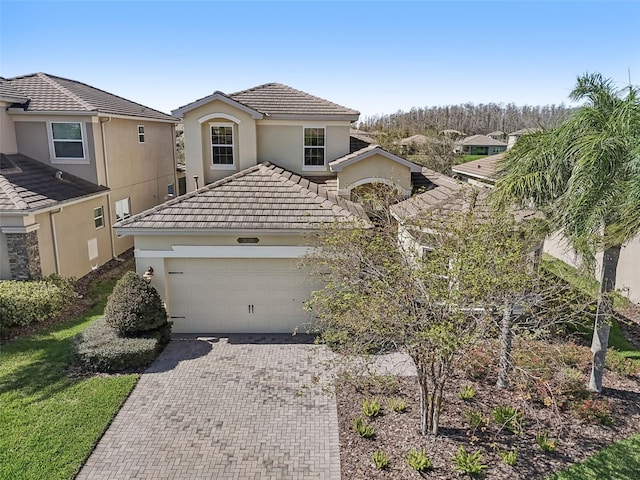 view of front facade featuring a garage, decorative driveway, a tiled roof, and stucco siding