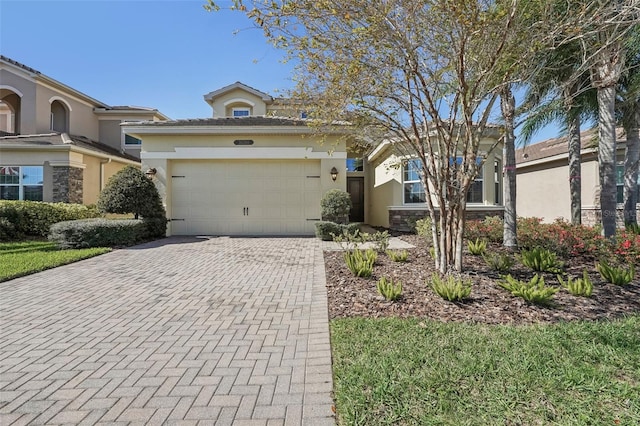 view of front facade with an attached garage, stone siding, decorative driveway, and stucco siding