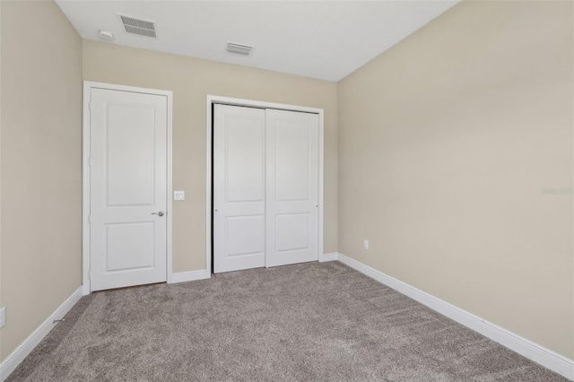 unfurnished bedroom with a closet, carpet, visible vents, and baseboards