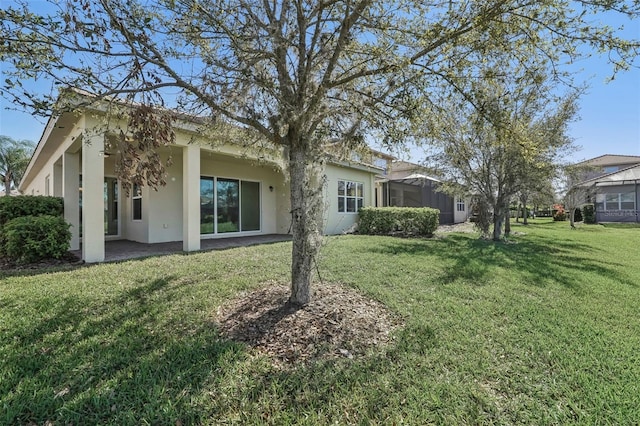 rear view of house with a yard, a patio, and stucco siding