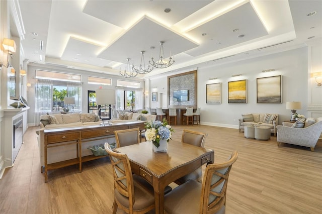 dining area with a tray ceiling, baseboards, and light wood finished floors