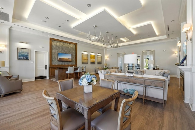 dining area with light wood-style floors, visible vents, a tray ceiling, and baseboards