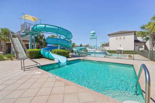 pool featuring a water slide, a patio area, and fence