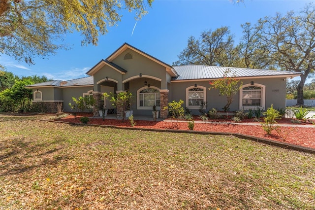 ranch-style house featuring stucco siding, metal roof, and a front lawn