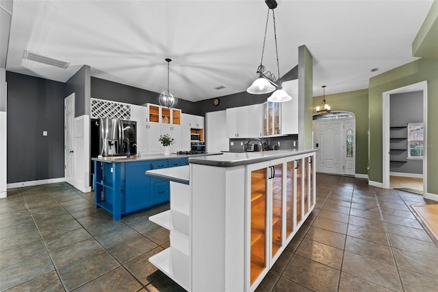 kitchen with visible vents, blue cabinetry, glass insert cabinets, stainless steel fridge, and open shelves