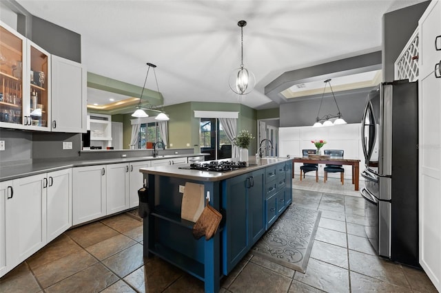 kitchen featuring blue cabinetry, black gas cooktop, freestanding refrigerator, and a tray ceiling