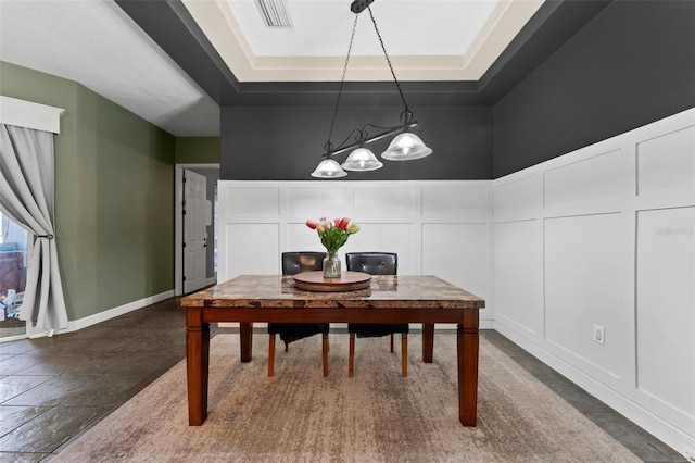 dining space with a tray ceiling, a decorative wall, and visible vents