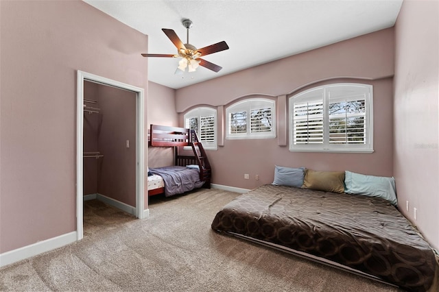 bedroom featuring baseboards, carpet floors, a spacious closet, and a ceiling fan