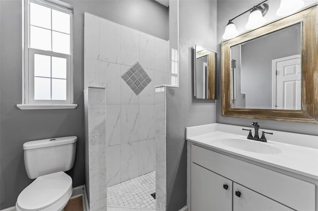 full bathroom with toilet, vanity, and a tile shower