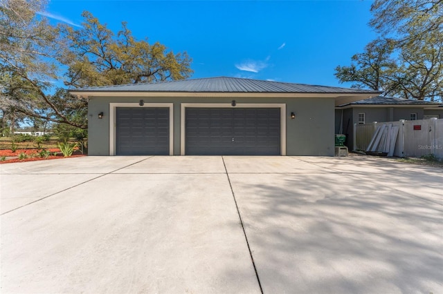 garage featuring concrete driveway and fence