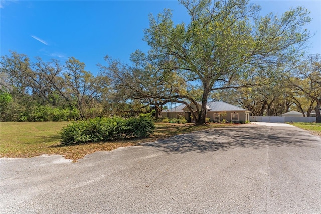 view of front of house featuring aphalt driveway, a front lawn, and fence