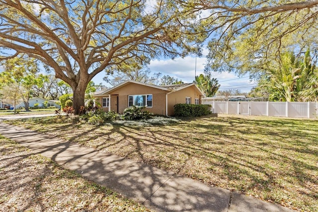 view of front facade with brick siding, a front yard, fence, and stucco siding