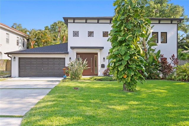 view of front of house with a front yard, an attached garage, driveway, and stucco siding