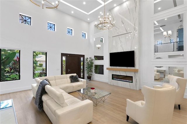 living area with wood finished floors, baseboards, recessed lighting, a fireplace, and a chandelier