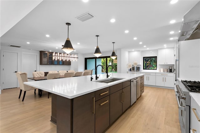 kitchen featuring visible vents, a sink, a spacious island, white cabinetry, and dark brown cabinetry