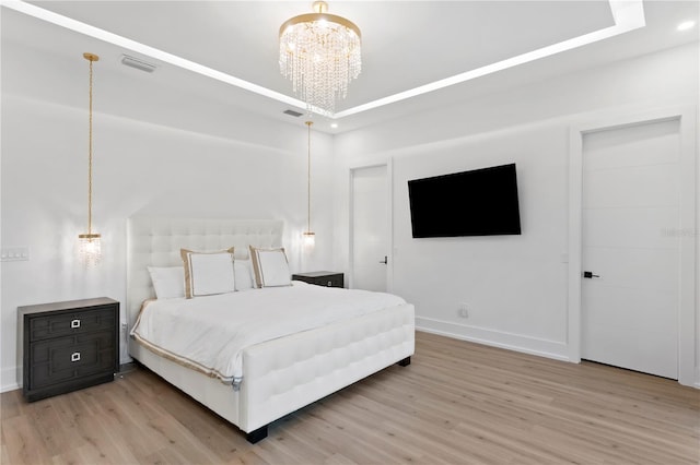 bedroom with visible vents, light wood finished floors, an inviting chandelier, a tray ceiling, and recessed lighting