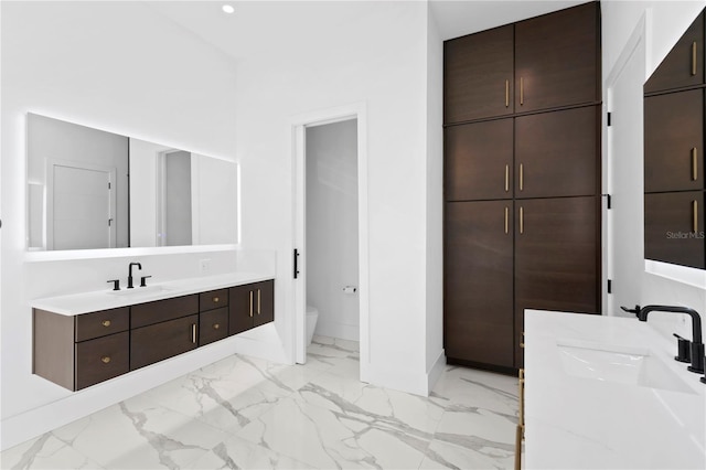 bathroom featuring a sink, two vanities, marble finish floor, and toilet