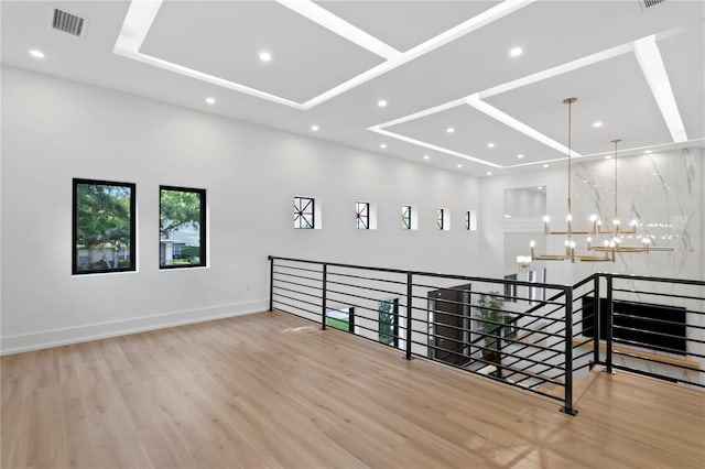 spare room featuring visible vents, baseboards, recessed lighting, an inviting chandelier, and wood finished floors