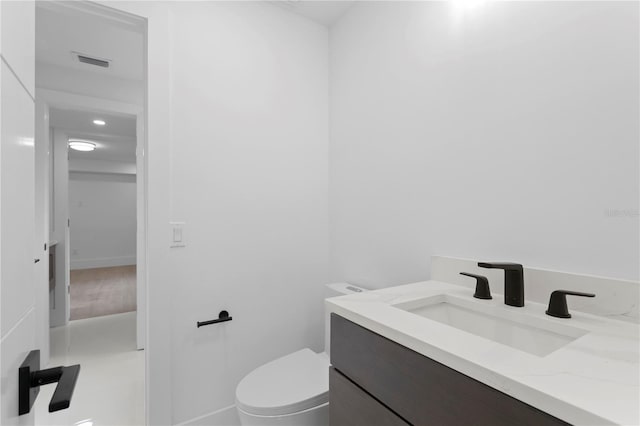 bathroom with vanity, toilet, and visible vents