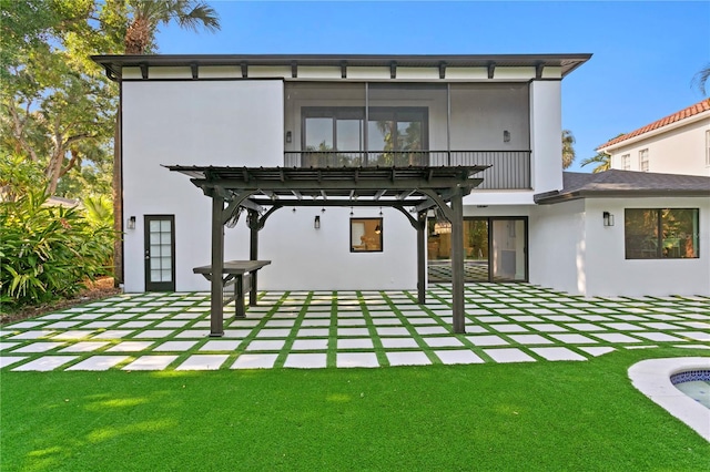 rear view of property with a yard, stucco siding, a pergola, and a patio