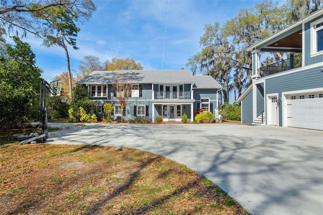 view of front of property featuring a garage, driveway, and a balcony