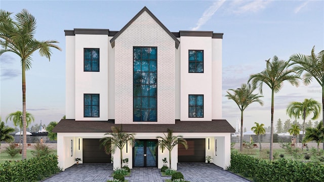 view of front facade with french doors, driveway, an attached garage, and stucco siding