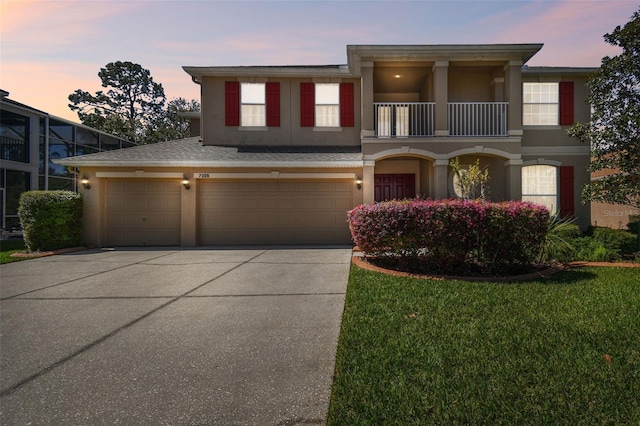 view of front facade with a garage, driveway, a balcony, and stucco siding