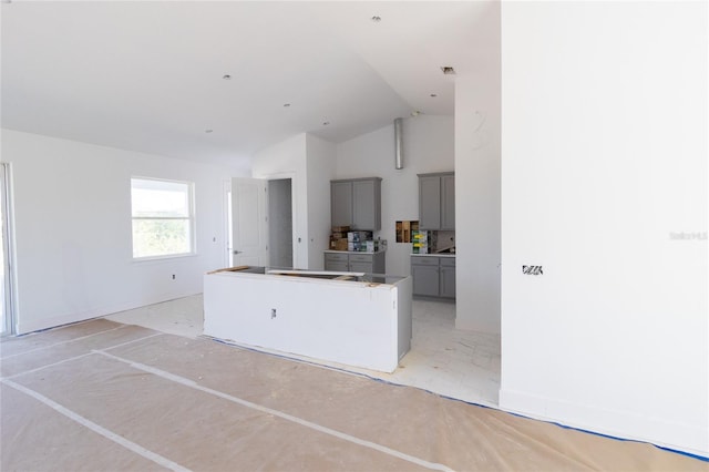 kitchen with high vaulted ceiling, a kitchen island, and gray cabinetry