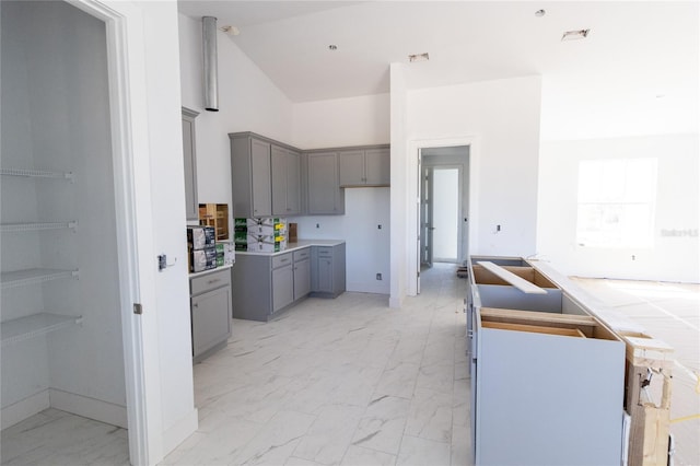 kitchen with a high ceiling, marble finish floor, visible vents, and gray cabinetry