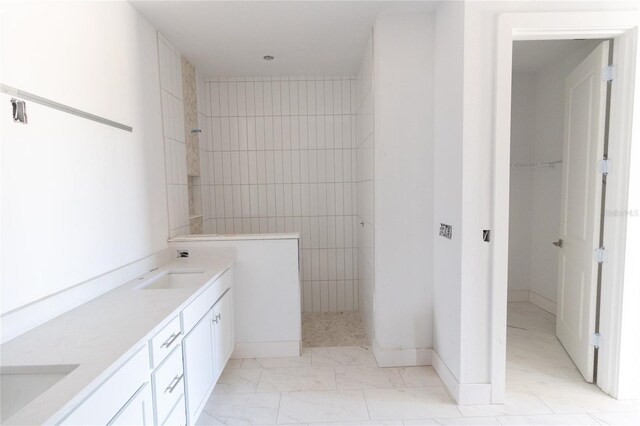 bathroom featuring double vanity, marble finish floor, and a walk in shower