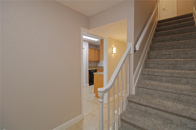 stairway with baseboards and tile patterned floors