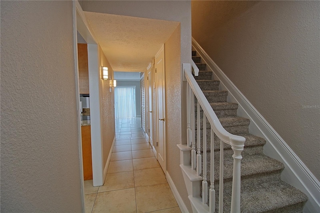 interior space with tile patterned flooring, a textured wall, and a textured ceiling