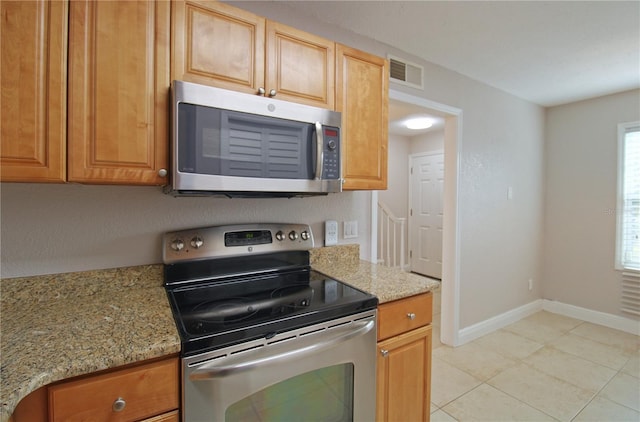 kitchen with light stone countertops, baseboards, visible vents, and stainless steel appliances