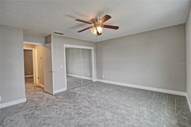 unfurnished bedroom with a textured ceiling, visible vents, baseboards, a closet, and carpet