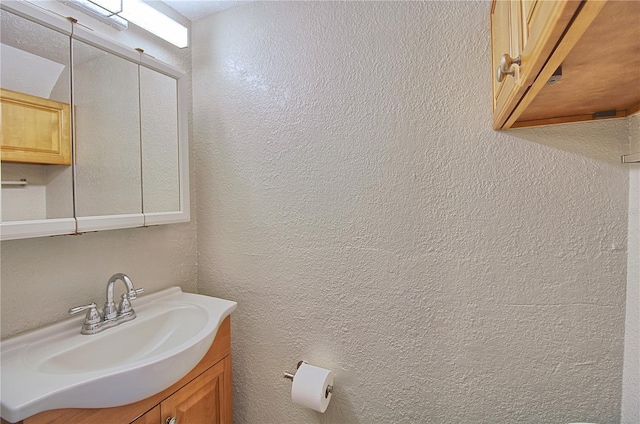 bathroom with a textured wall and vanity