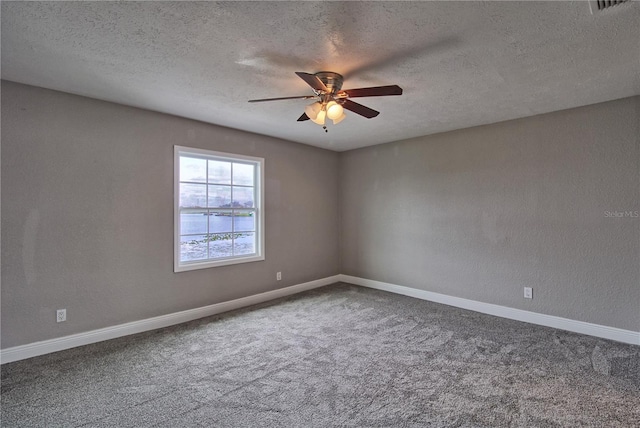 empty room featuring carpet floors, a textured wall, a ceiling fan, a textured ceiling, and baseboards